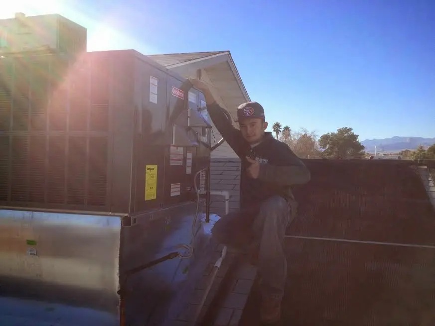 HVAC technician performing AC Tune-Up on a rooftop unit in Allouez